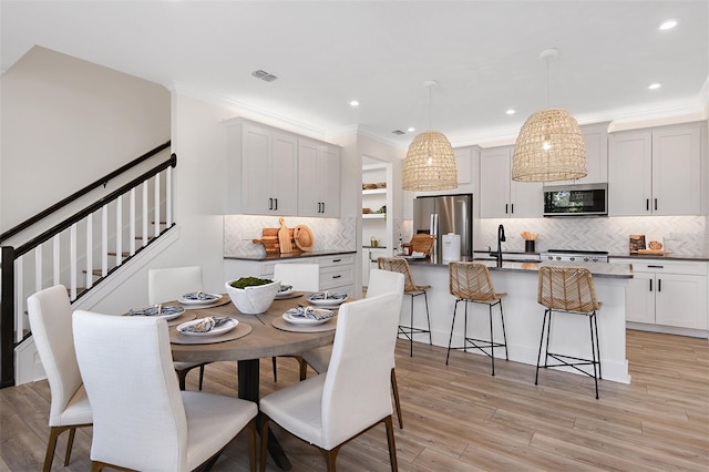 dining room with sink, light hardwood / wood-style flooring, and crown molding