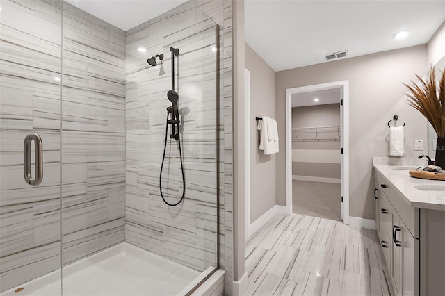 bathroom featuring a shower with door and vanity