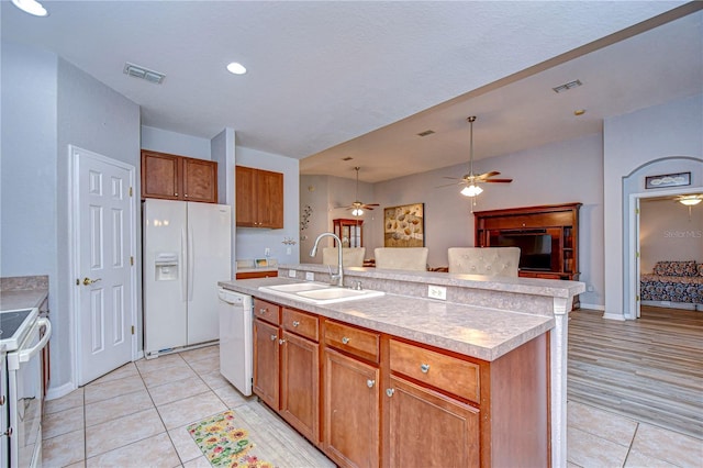 kitchen featuring a kitchen island with sink, sink, pendant lighting, light tile patterned floors, and white appliances