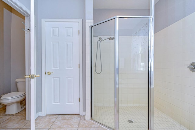 bathroom with a shower with door, toilet, and tile patterned flooring