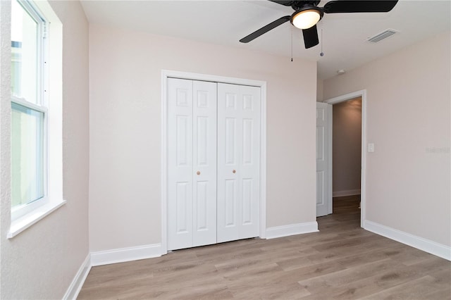 unfurnished bedroom featuring light wood-style flooring, a closet, visible vents, and baseboards