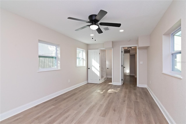 unfurnished bedroom with light wood-style flooring, visible vents, baseboards, and a walk in closet