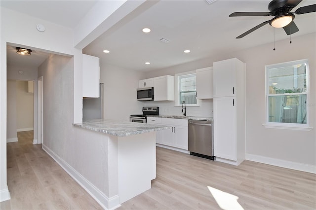 kitchen with light wood-style flooring, white cabinetry, baseboards, appliances with stainless steel finishes, and decorative backsplash