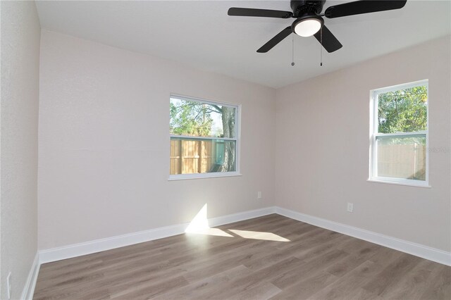 unfurnished room featuring a healthy amount of sunlight, baseboards, and wood finished floors