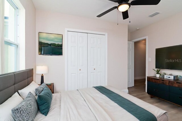 bedroom with a ceiling fan, a closet, visible vents, and light wood finished floors