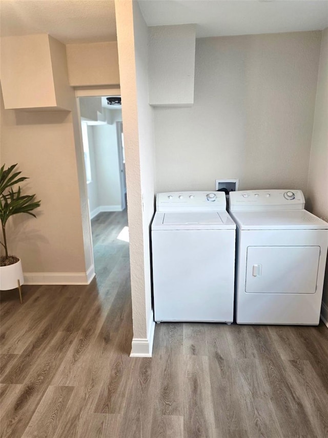 washroom with laundry area, baseboards, separate washer and dryer, and wood finished floors