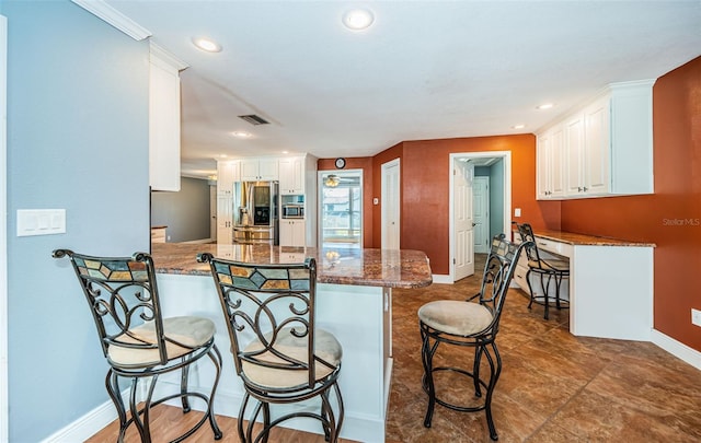 kitchen with a kitchen breakfast bar, kitchen peninsula, stainless steel refrigerator with ice dispenser, stone counters, and white cabinetry