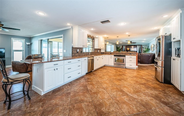 kitchen with a breakfast bar area, appliances with stainless steel finishes, kitchen peninsula, and white cabinetry