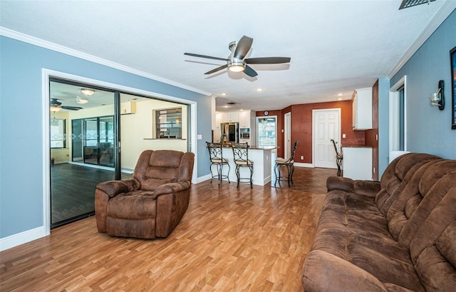 living room featuring crown molding, light wood-type flooring, and ceiling fan