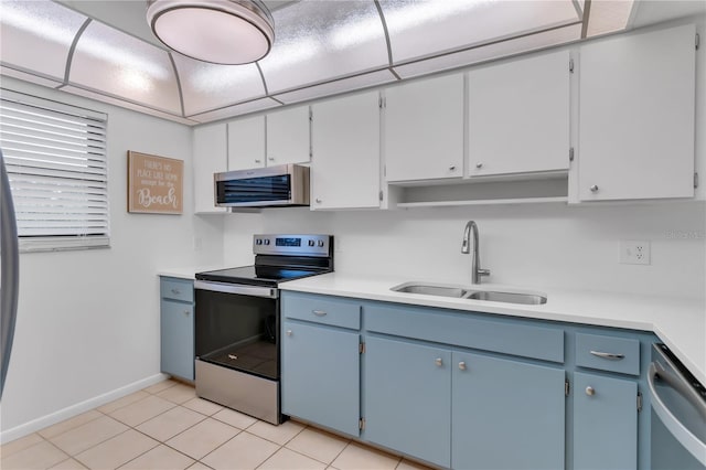 kitchen featuring white cabinets, light tile patterned flooring, stainless steel appliances, sink, and blue cabinets