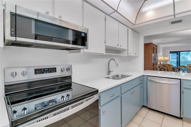 kitchen featuring light tile patterned floors, appliances with stainless steel finishes, sink, and blue cabinets