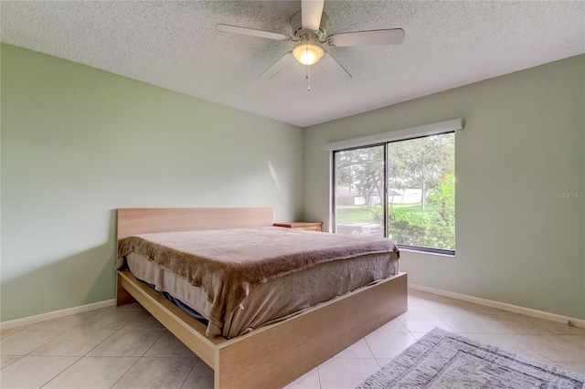 tiled bedroom with ceiling fan and a textured ceiling