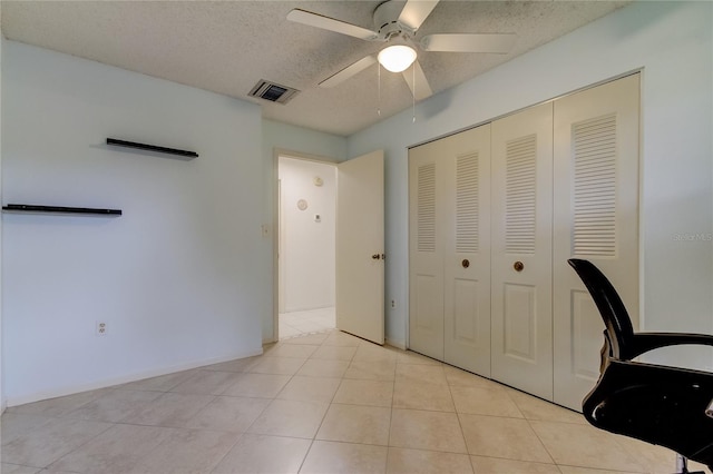 unfurnished office featuring a textured ceiling, light tile patterned floors, and ceiling fan