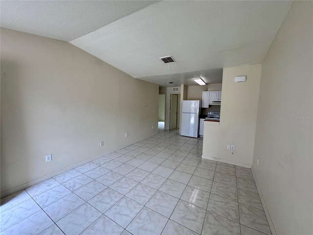 spare room with light tile patterned floors, a textured ceiling, and vaulted ceiling