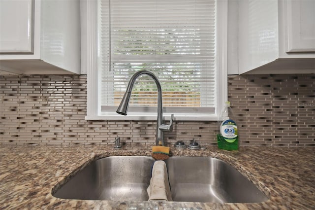 details with sink, dark stone countertops, white cabinets, and decorative backsplash