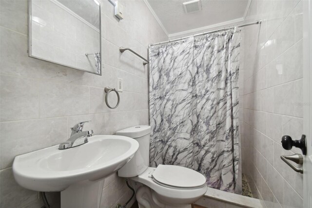 bathroom featuring sink, tile walls, ornamental molding, a textured ceiling, and curtained shower