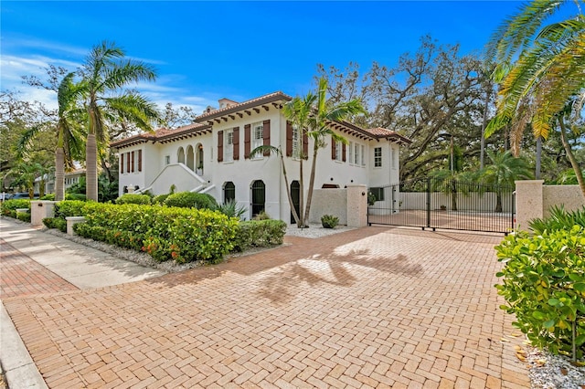 view of side of home with a tiled roof, a gate, fence, and stucco siding