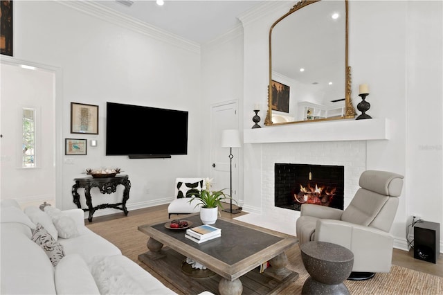 living room featuring ornamental molding, a brick fireplace, and light wood-type flooring