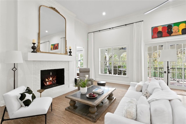 living room with a brick fireplace, hardwood / wood-style flooring, crown molding, and a wealth of natural light