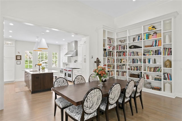 dining room featuring light hardwood / wood-style floors, ornamental molding, and sink