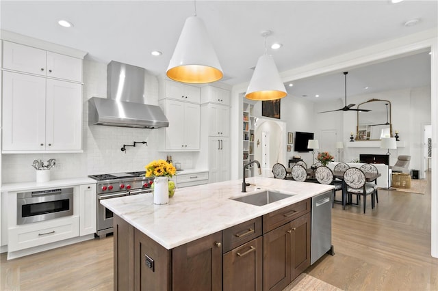 kitchen with white cabinetry, wall chimney range hood, appliances with stainless steel finishes, and sink