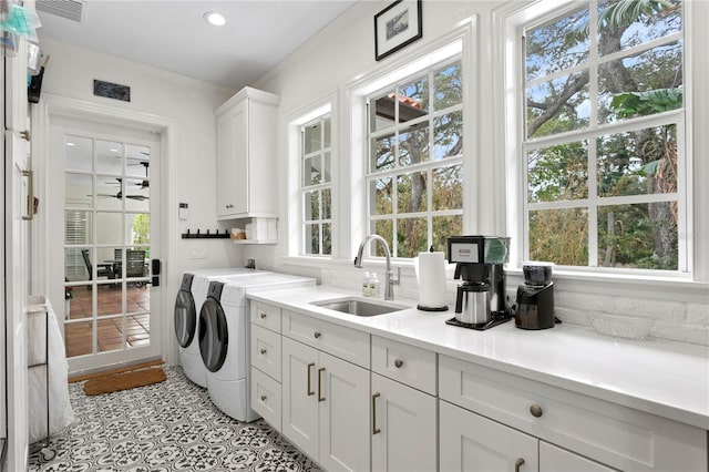 washroom with sink, cabinets, a wealth of natural light, and washer and clothes dryer