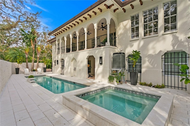 back of house with a patio, a balcony, a swimming pool with hot tub, and ceiling fan