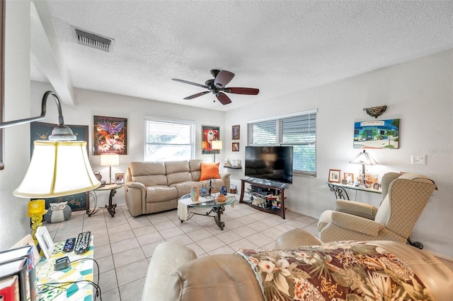 living room with ceiling fan, a textured ceiling, and light tile patterned flooring