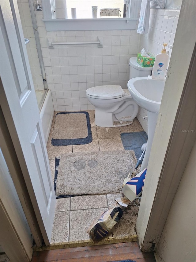 bathroom with toilet, bathing tub / shower combination, and tile walls