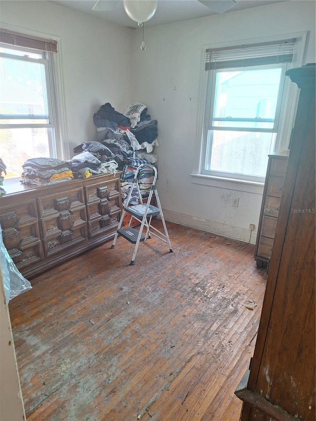 unfurnished bedroom with ceiling fan, multiple windows, and hardwood / wood-style floors