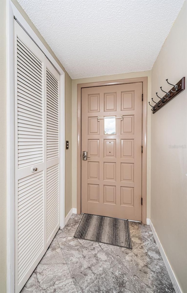 doorway to outside with a textured ceiling