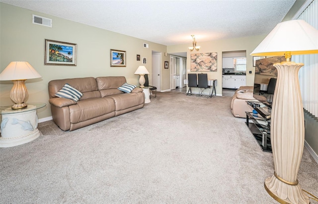 carpeted living room with a notable chandelier and a textured ceiling