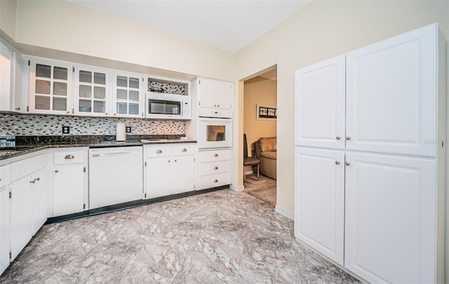 kitchen featuring white appliances, dark stone countertops, decorative backsplash, and white cabinets