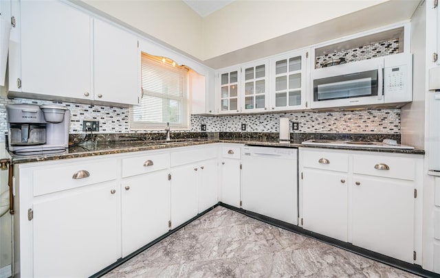 kitchen featuring white cabinets, dark stone countertops, backsplash, and white appliances