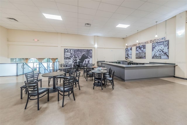 dining space featuring a drop ceiling and a high ceiling