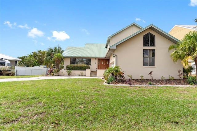 view of front of property with metal roof, a front yard, fence, and stucco siding