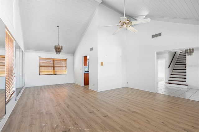 unfurnished living room featuring lofted ceiling, ceiling fan with notable chandelier, visible vents, stairway, and light wood-type flooring