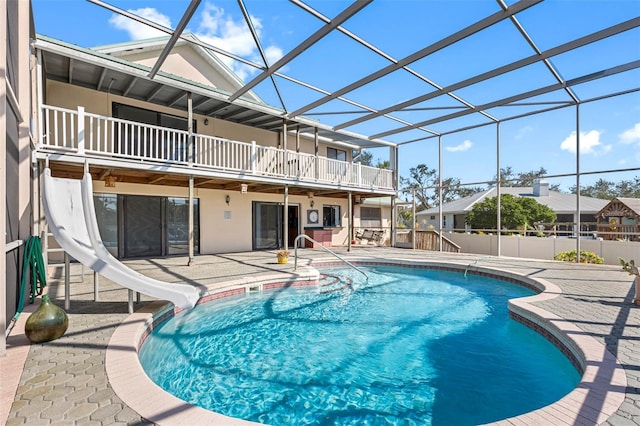 view of swimming pool with a water slide, glass enclosure, and a patio area