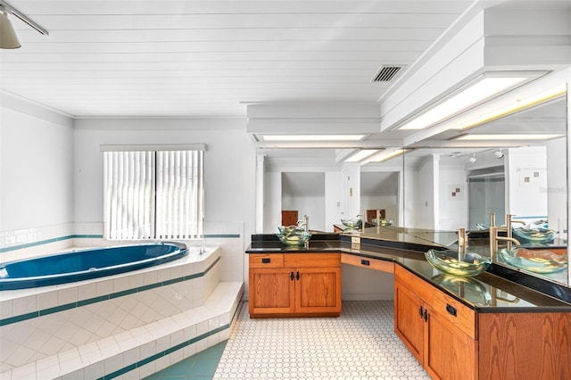 bathroom featuring vanity and tiled bath