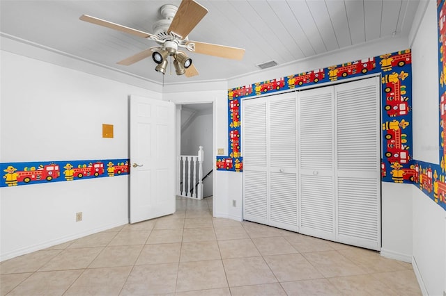 unfurnished bedroom with light tile patterned floors, a closet, and ceiling fan