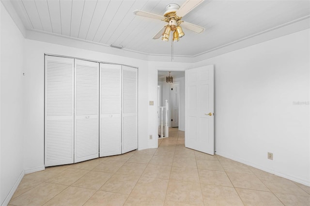 unfurnished bedroom featuring crown molding, light tile patterned floors, a closet, a ceiling fan, and baseboards