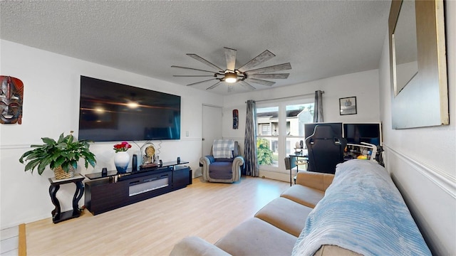 living room with a textured ceiling, wood-type flooring, and ceiling fan