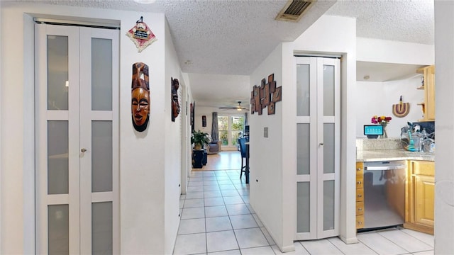 hallway with a textured ceiling and light tile patterned floors