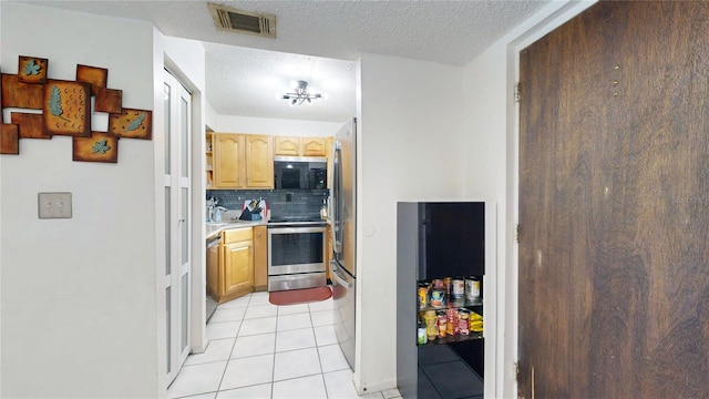 kitchen featuring decorative backsplash, appliances with stainless steel finishes, a textured ceiling, and light tile patterned flooring