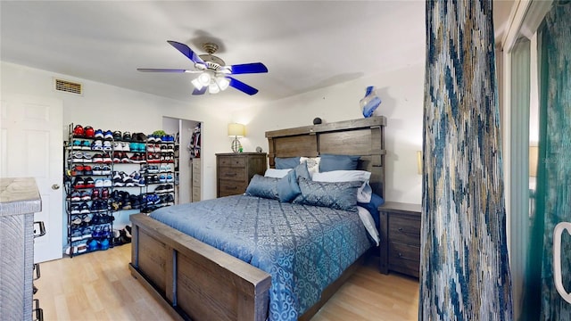 bedroom featuring light hardwood / wood-style flooring, a barn door, and ceiling fan