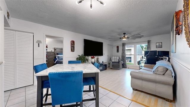 living room featuring light hardwood / wood-style floors, a textured ceiling, and ceiling fan