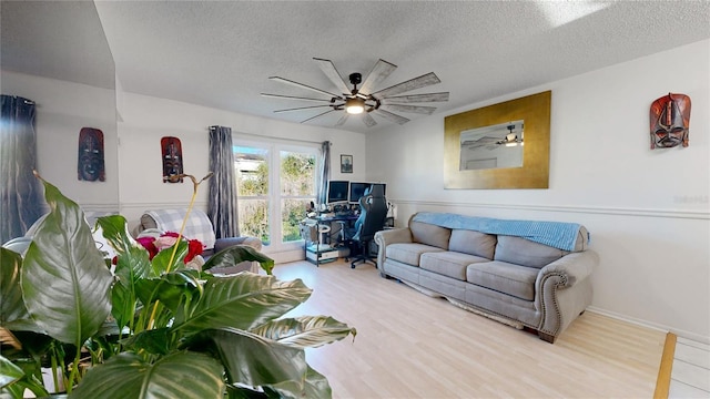 living room with ceiling fan, a textured ceiling, and light wood-type flooring