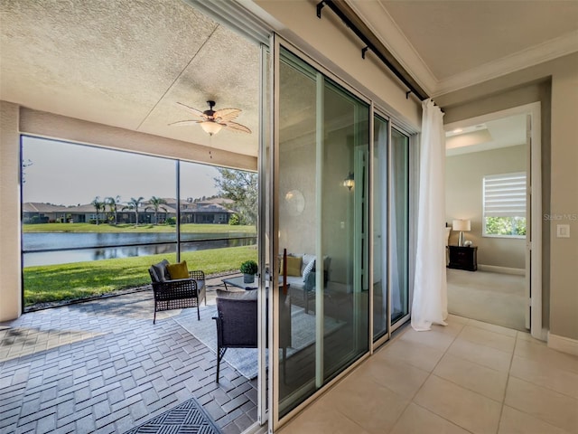 interior space featuring a healthy amount of sunlight, light tile patterned floors, crown molding, ceiling fan, and a water view