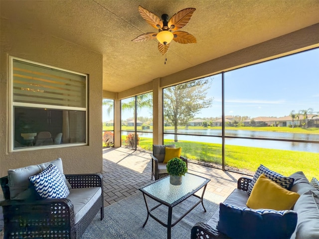 sunroom with ceiling fan and a water view