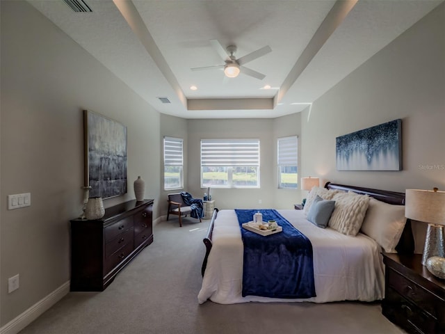 bedroom featuring ceiling fan, light colored carpet, and a raised ceiling